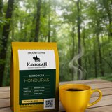 Kaveolah Honduras coffee package and yellow mug with steam on a wooden surface with a forest background